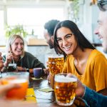 Young people dining having fun drinking beer at brewery pub